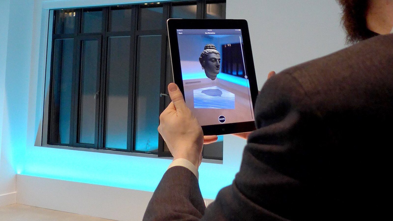 A tablet showing a sculpture placed in augmented reality